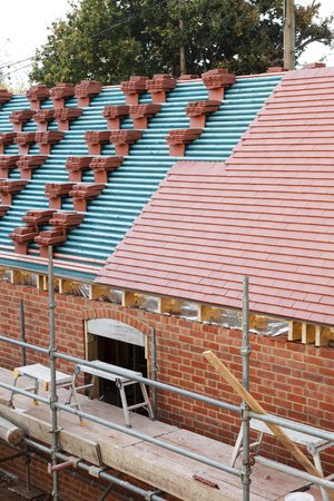 A roof on a building site in the process of being tiled with plain clay tilesの写真素材