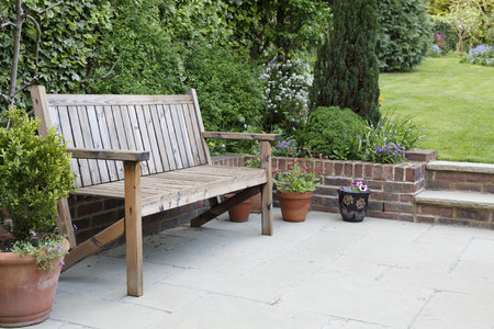 British back garden with a paved patio and traditional wooden benchの写真素材