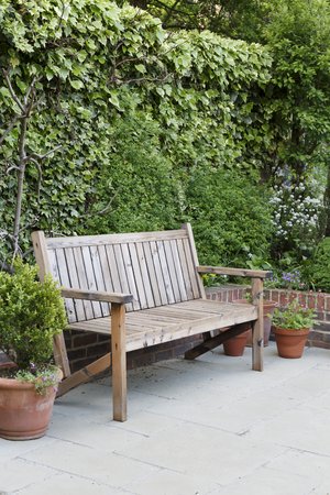 Traditional wooden garden bench on a patio in an English gardenの写真素材