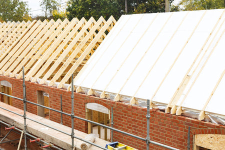Installation of solid insulation sheets into roof trusses on a house buildの写真素材