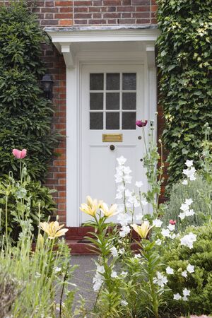 Half-glazed wooden front door of a period house in London with an attractive flower gardenの写真素材