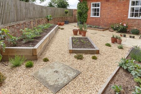 Oak sleeper raised beds in a courtyard garden design with hard landscpaing, gravel and terracotta potsの写真素材