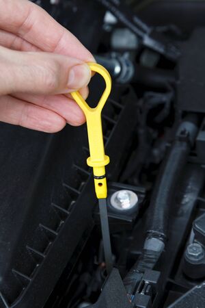 Checking oil level with dipstick in a car engine.の写真素材
