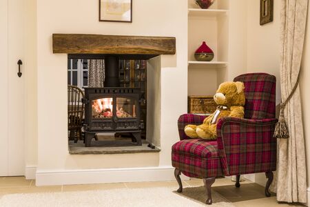 Cosy fireplace with wood burning stove and teddy bear in a living room home interior, UKの写真素材