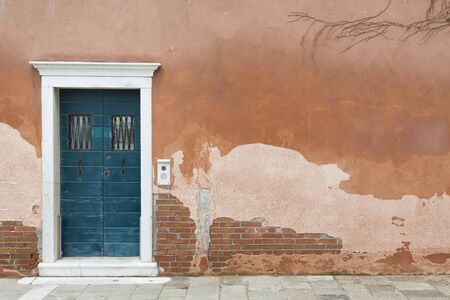 Vintage front door painted blue and a wall with old weathered render in Venice, Italyの写真素材