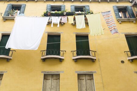 Washing drying airing on a line outside old houses with wooden shutters in a street in Venice, Italyの写真素材