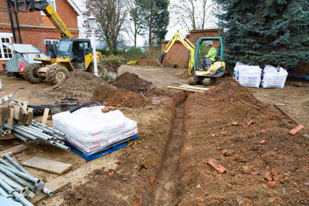 BUCKINGHAM, UK - December 02, 2016. Digger driver, digging a trench for drains on a UK building siteのeditorial素材