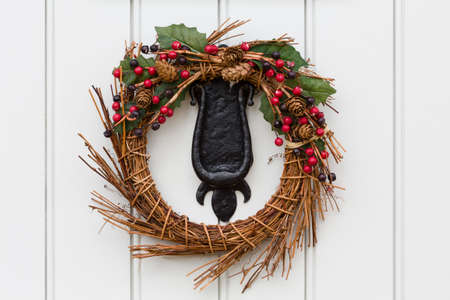 Detail of a Christmas wreath or garland on the cast iron knocker of a traditional painted wooden doorの写真素材