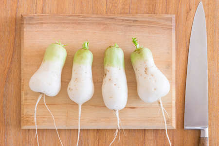 Homegrown mooli radish (daikon) roots on a chopping board and kitchen table in UK. Flat lay food ingredientsの写真素材