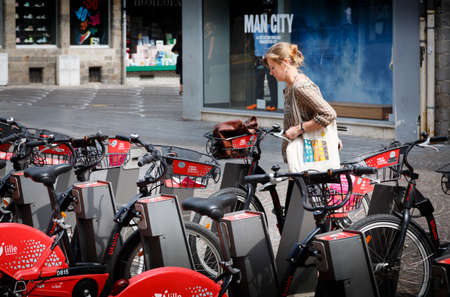 LILLE, FRANCE - July 18, 2013. French woman using a free rental bike in Lille, Franceのeditorial素材