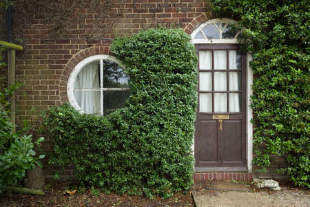 BUCKINGHAM, UK - August 05, 2020. Facade of a small UK cottage with round window and front doorのeditorial素材
