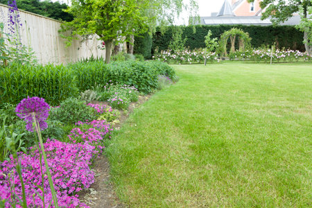 Large English garden in early summer or late spring with flowers in border and lawn. Example of landscaped garden design and gardening, UKの写真素材