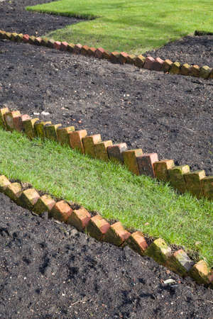 Preparing a new empty flowerbed in a UK garden with sawtooth brick edgingの写真素材