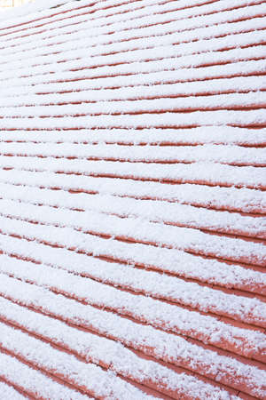 Detail of pitched roof with new plain clay roof tiles covered in snow in winter, UKの写真素材