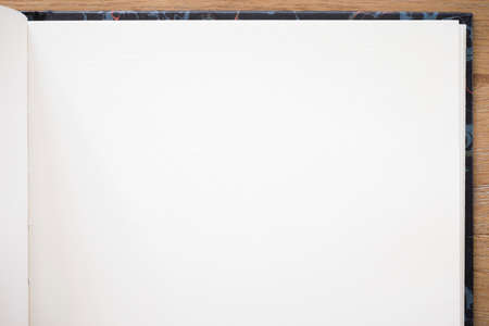 Notebook with plain white paper and hardback open on a wooden deskの写真素材