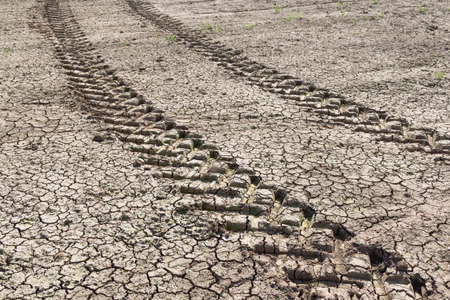 Tractor tracks through a dry barren field during drought on a UK farm. Background, texture or pattern depicting concepts of global warming and climate change.の写真素材