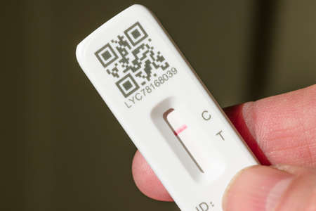 UNITED KINGDOM - March 26, 2022. Man holding a lateral flow test strip (LFT or LFD) with negative result in hand, Covid (COVID-19) testing, UKのeditorial素材