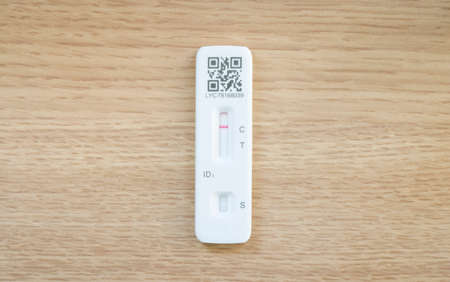 UNITED KINGDOM - March 26, 2022. Flat lay of Covid LFT test strip on a wooden desk with copy space. Negative Lateral Flow Test result, UKのeditorial素材