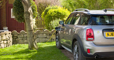 BUCKINGHAMSHIRE, UK - April 09, 2022. Electric car charging at home. Electric Mini Countryman parked outside a house, plugged in and recharging.のeditorial素材
