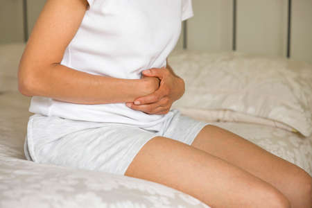 Stomach pain, Asian Indian woman holding her stomach in pain