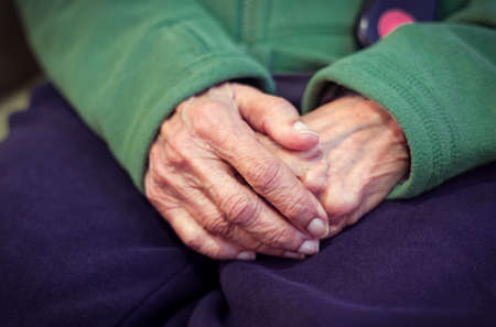 Close-up of the hands of an old Asian Indian woman with wrinkled skin. Depicts loneliness, worry, dementia, and mental health concepts.の写真素材