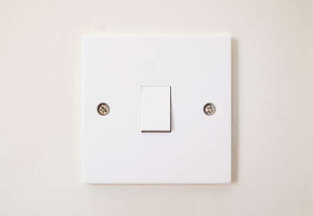 White plastic room light switch on a wall, home interior lighting, UKの写真素材