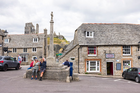 DORSET, UK - July 06, 2022. Tourists sitting on Queen Victoria Jubilee monument at Corfe Castle Villageのeditorial素材