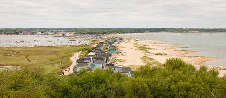 DORSET, UK - July 07, 2022. Beach huts on Hengistbury Head with Christchurch Harbour in the...