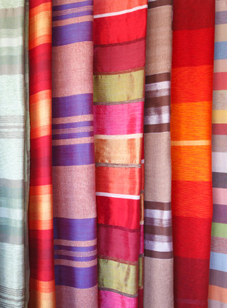Colorful swatches of silk fabric with African patterns hanging on a street market stall in Medina...