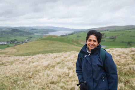 British Asian Indian woman in waterproof coat hiking in Snowdonia National Park near Lake Bala,...