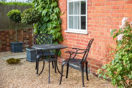 Landscaped garden design with bistro table and chairs on gravel in traditional UK gardenの写真素材