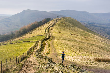 PEAK DISTRICT, UK - March 02, 2023. Man trail running on Hollins Cross, Derbyshire, UKのeditorial素材
