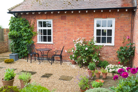 UK cottage garden with hard landscaping, patio furniture bistro table and chairsの写真素材