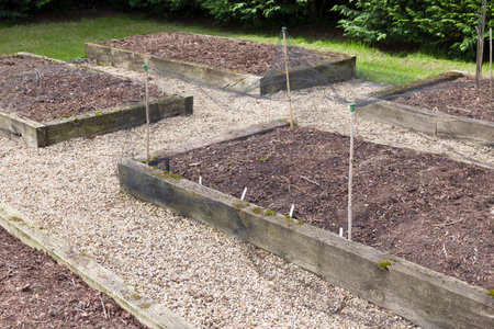 Empty wooden sleeper raised beds in a vegetable garden in spring. Preparing vegetable beds in a UK gardenの写真素材