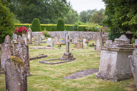 Old English cemetery with weathered gravestones covered in moss and lichen. Peaceful rural graveyard, UK.  No identifiable gravestones.の写真素材