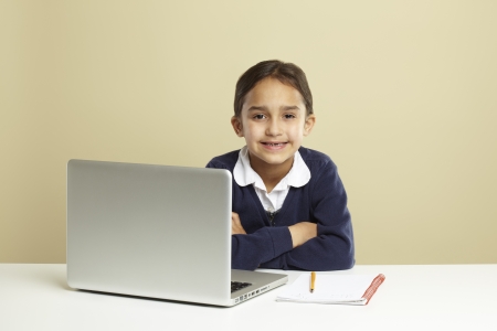 Young girl using laptop on white desk with homeworkの写真素材