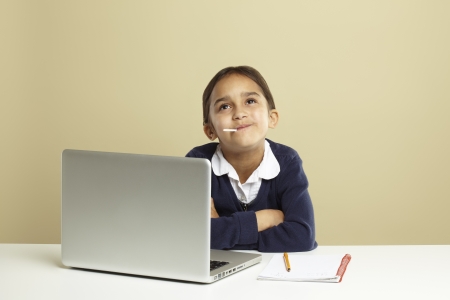 Young girl using laptop on white desk with homeworkの写真素材