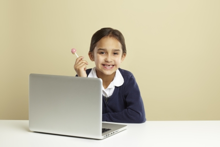 Young girl using laptop on white deskの写真素材
