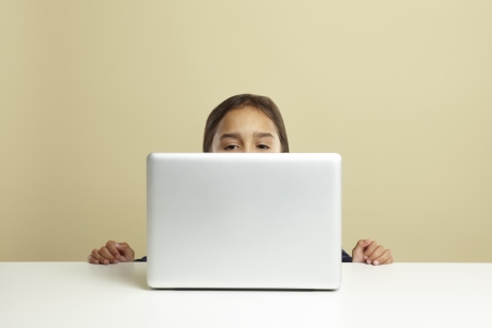 Young girl using laptop on white deskの写真素材