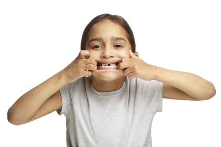 Young girl with missing front tooth on white backgroundの写真素材