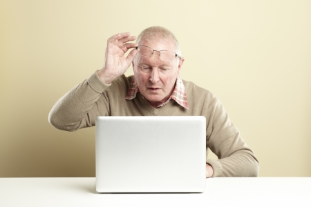 Senior man using laptop whilst looking confusedの写真素材
