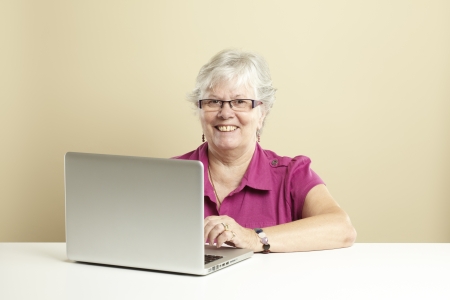 Senior woman using laptop whilst smilingの写真素材