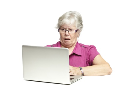 Senior woman using laptop whilst looking shocked, on white backgroundの写真素材