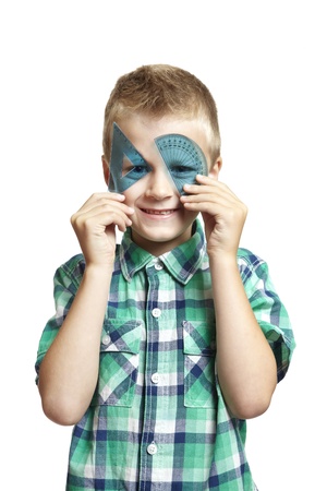 8 year old school boy with blue set square and protractor over his eyes on white backgroundの写真素材