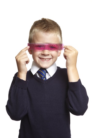 8 year old school boy with pink ruler over his eyes on white backgroundの写真素材