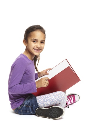 8 year old school girl sitting reading book smiling on white backgroundの写真素材