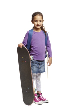 8 year old school girl with skateboard and backpack on white backgroundの写真素材
