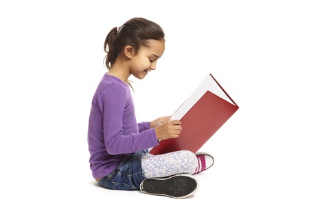 8 year old school girl sitting reading book smiling on white backgroundの写真素材