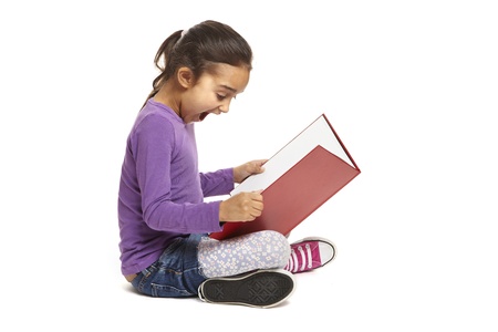 8 year old school girl sitting reading book looking shocked on white backgroundの写真素材
