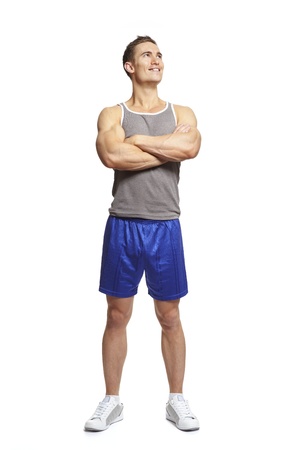 Muscular young man in sports outfit arms folded looking up on white backgroundの写真素材